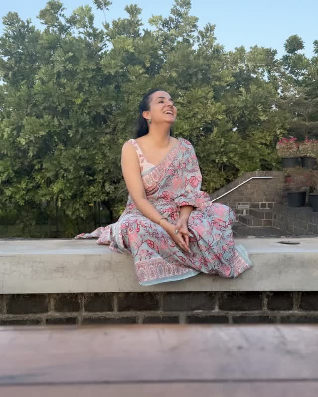 Neeru sitting on a garden wall at golden hour, laughing