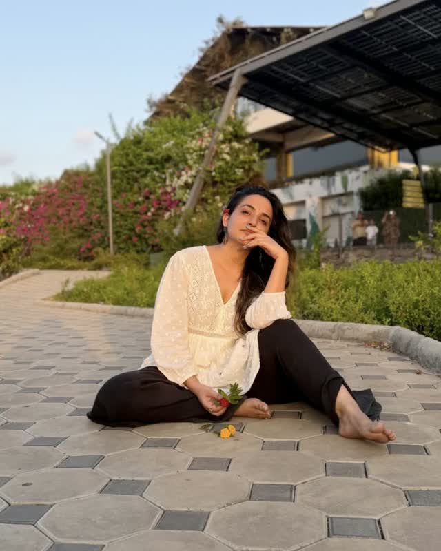 Neeru sitting outdoors among flowering plants